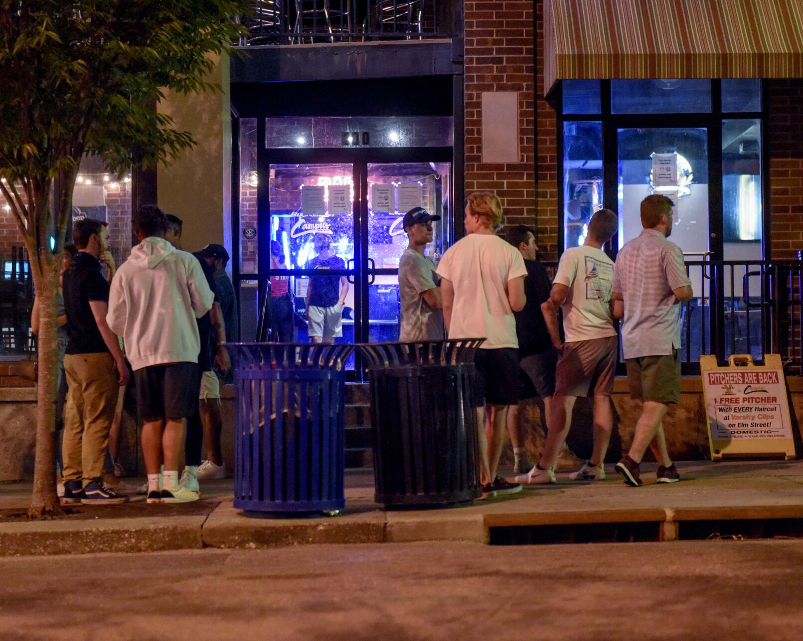 A group of men stand outside of Campus Bar and Grill shortly after close